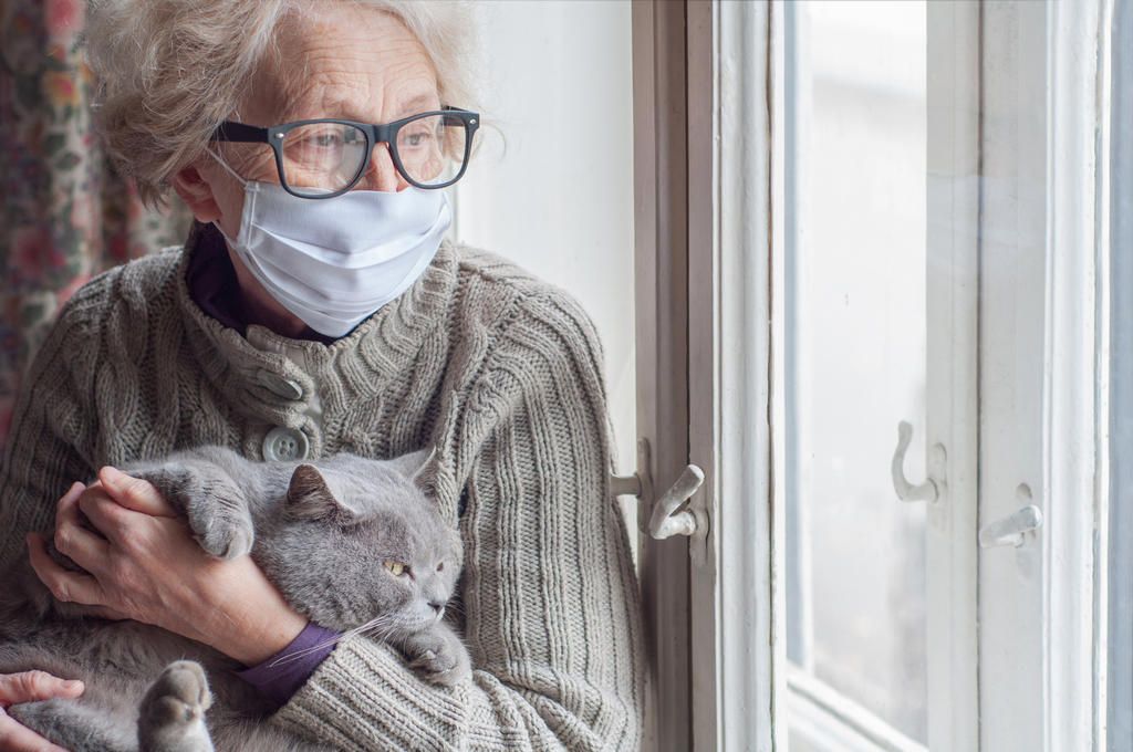 Elderly,Woman,In,Protective,Mask,Holding,A,Cat,Looks,Out