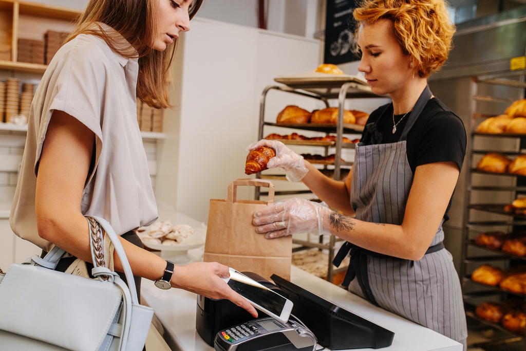 Baker,Standing,Behind,Cash,Register,In,A,Shop,,Placing,Freshly